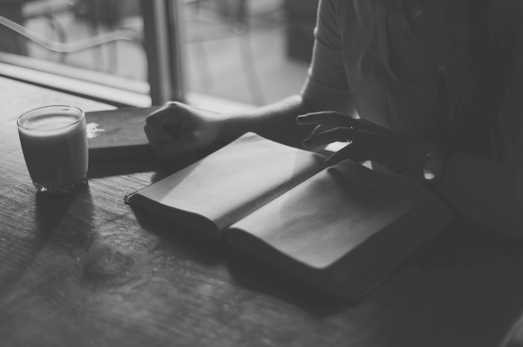 Person writing in a notebook at a wooden desk